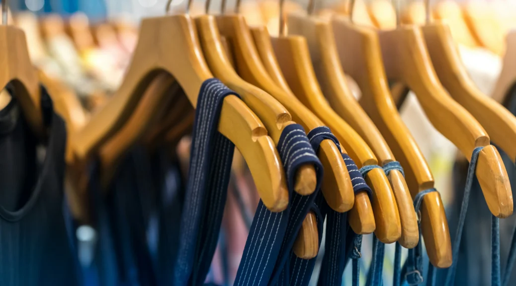 vêtements bleu marine sur cintres en bois dans un magasin de mode