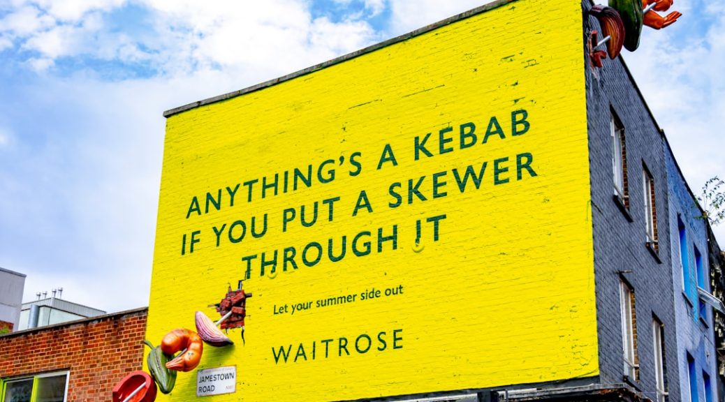 Yellow billboard with text about kebabs and skewers.