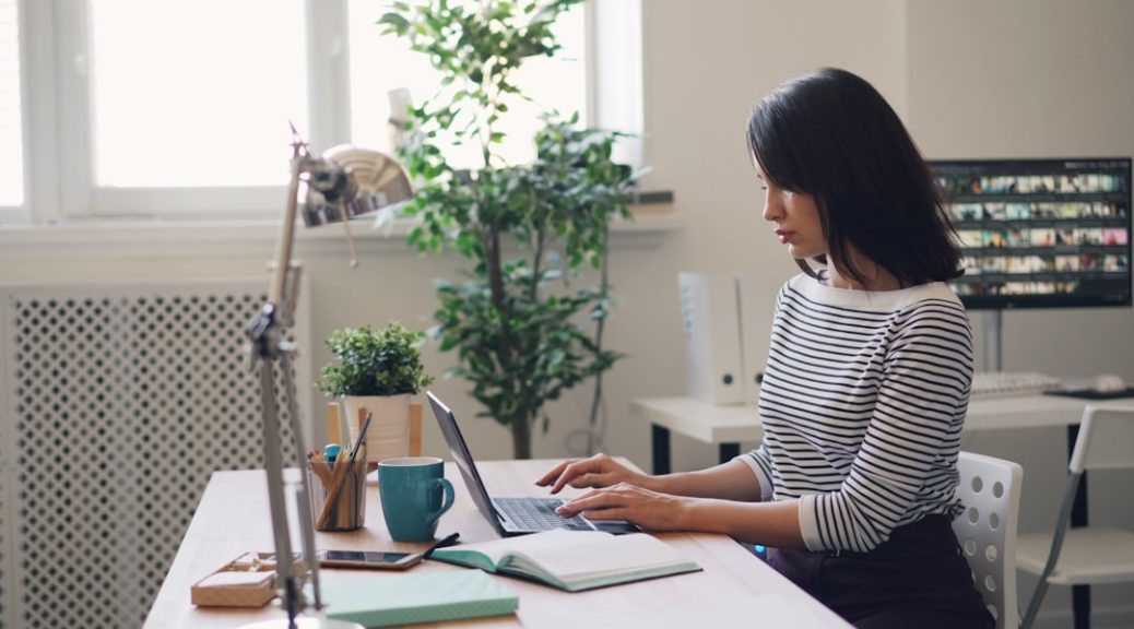 a woman sitting at a desk using a laptop computer